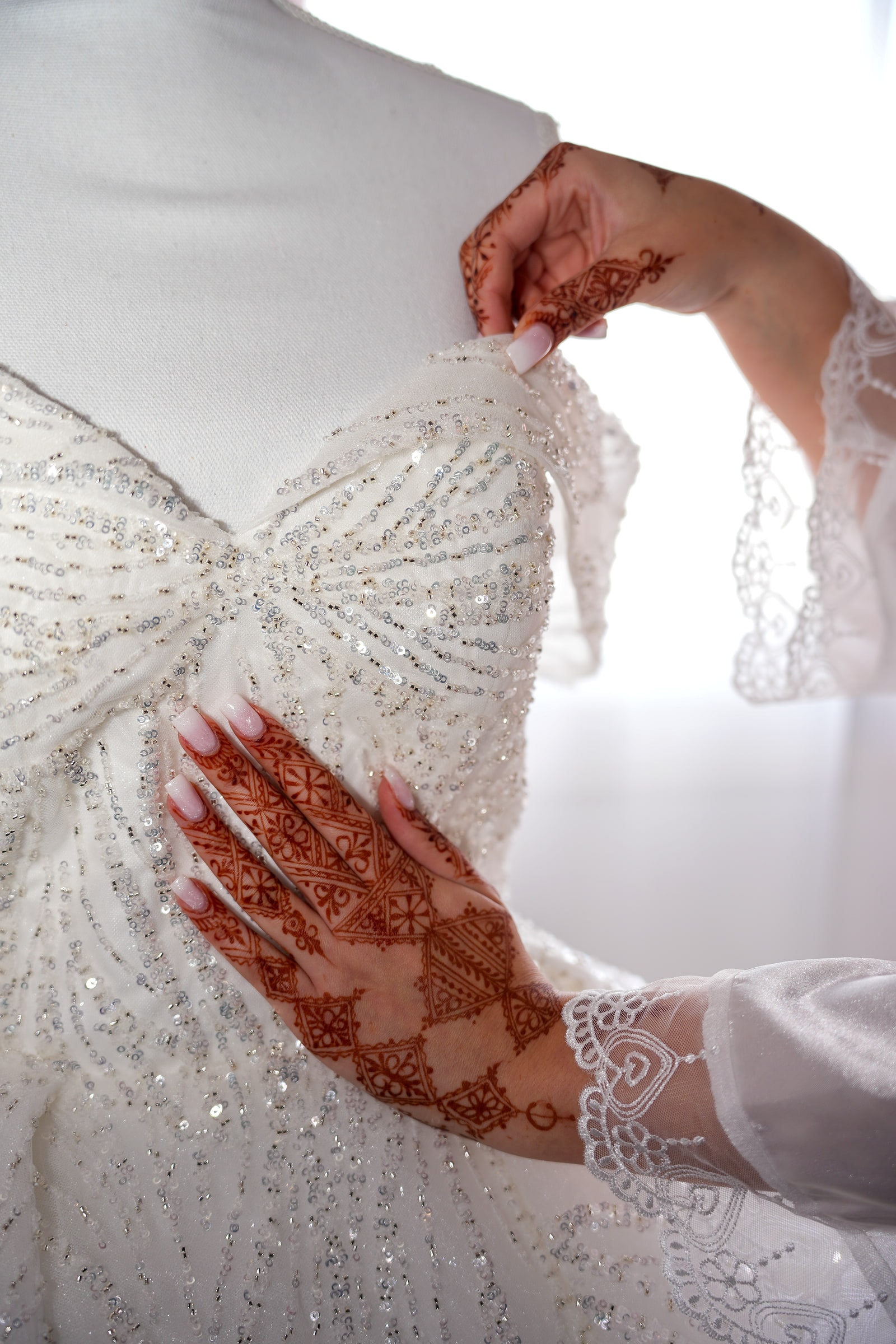 La main de la mariée, couverte de henné, posée sur la robe