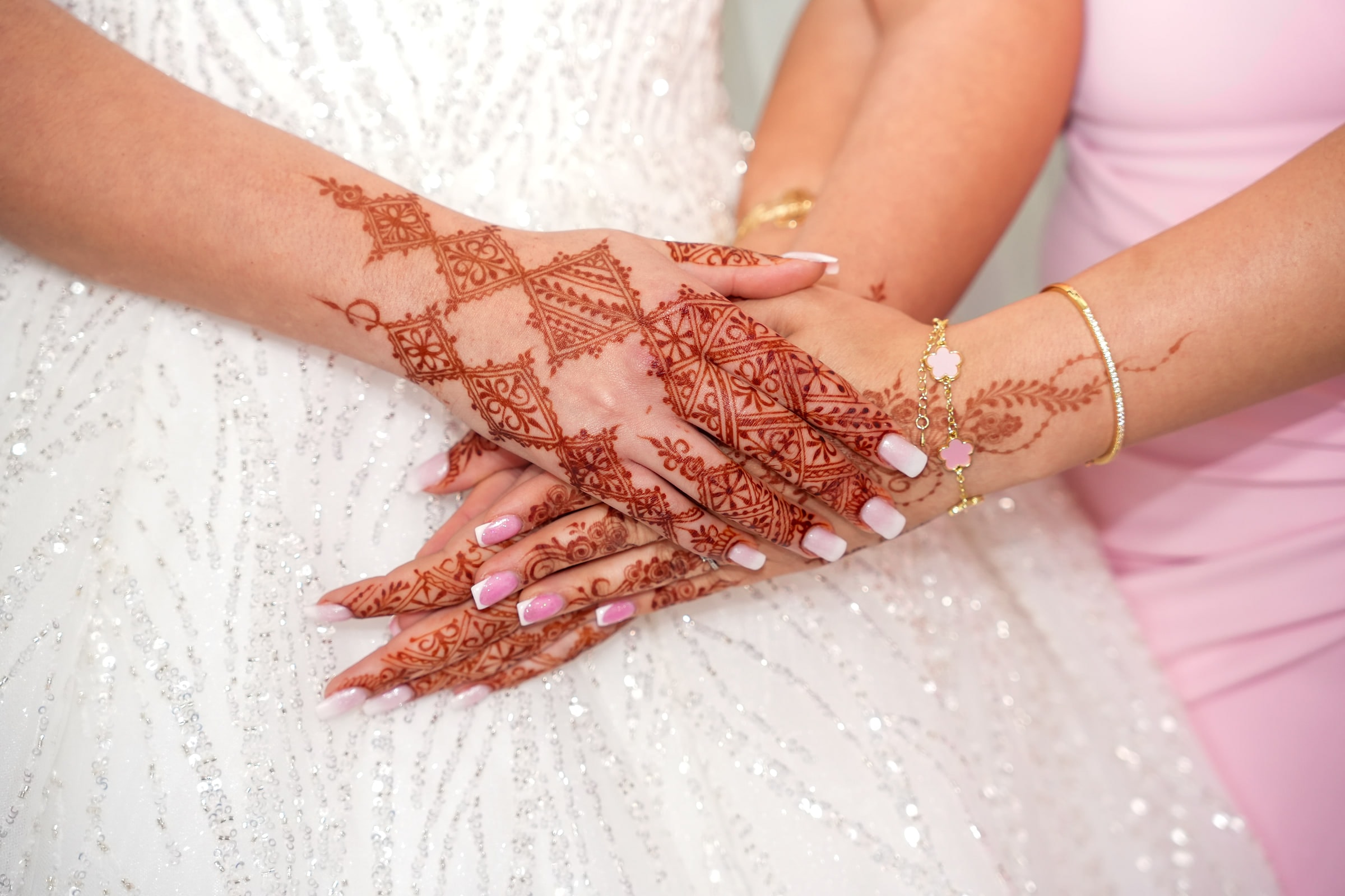Les mains de la mariée ornées de henné, sur la robe brodée