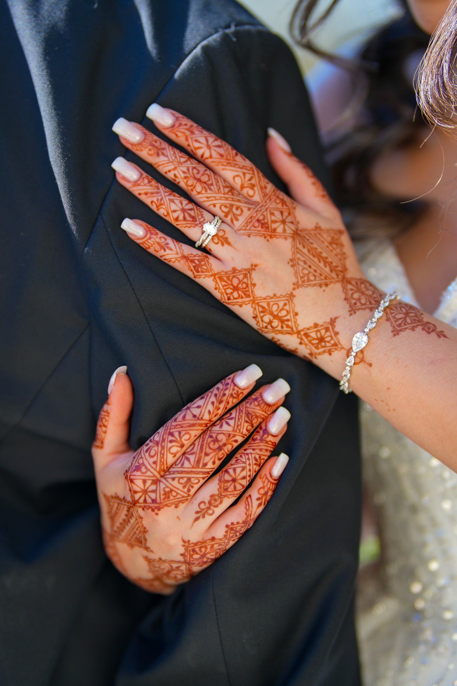 Les mains de la mariée posées sur la veste du marié