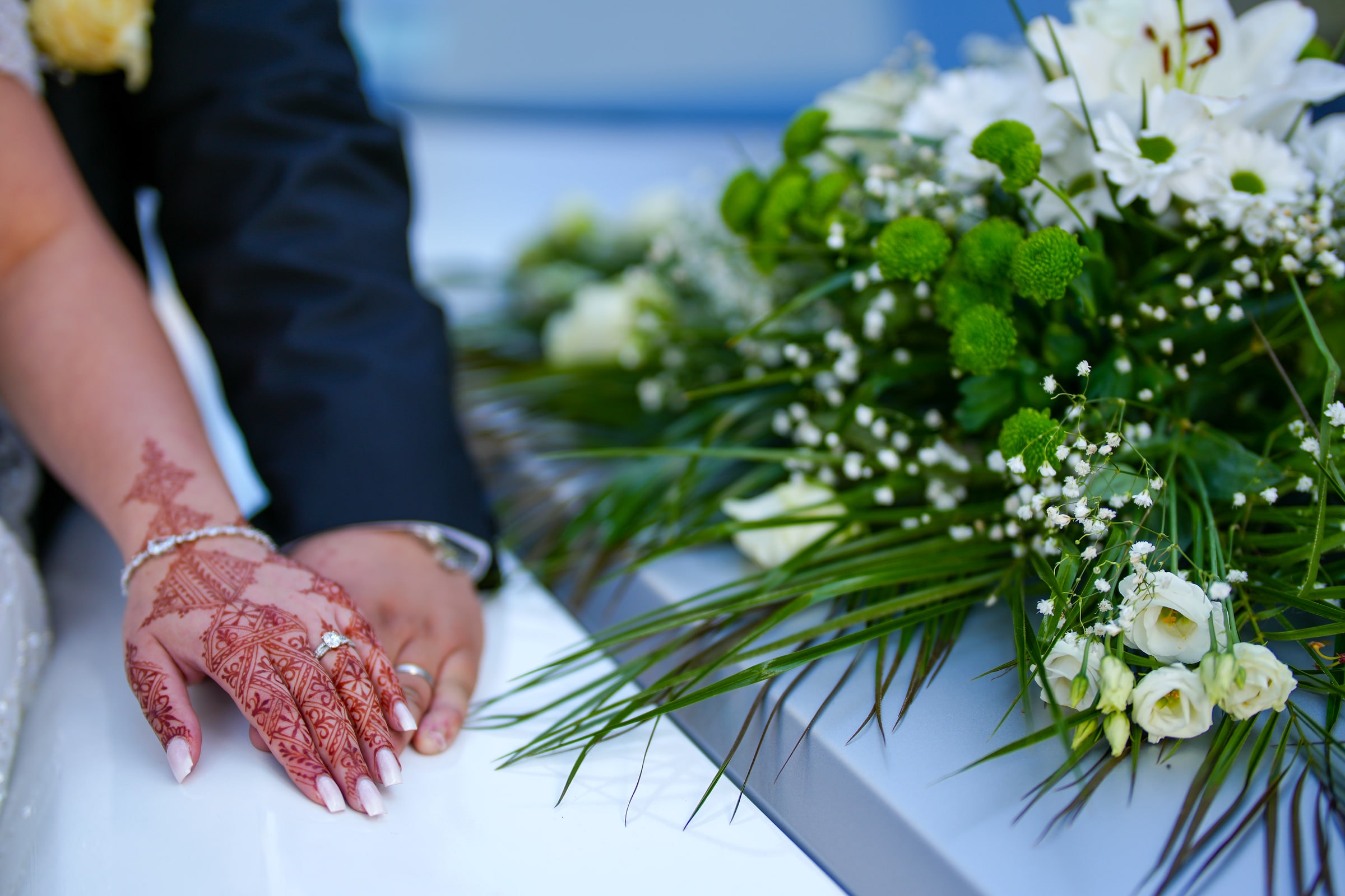 Les mains des mariés sur le capot fleuri de la voiture