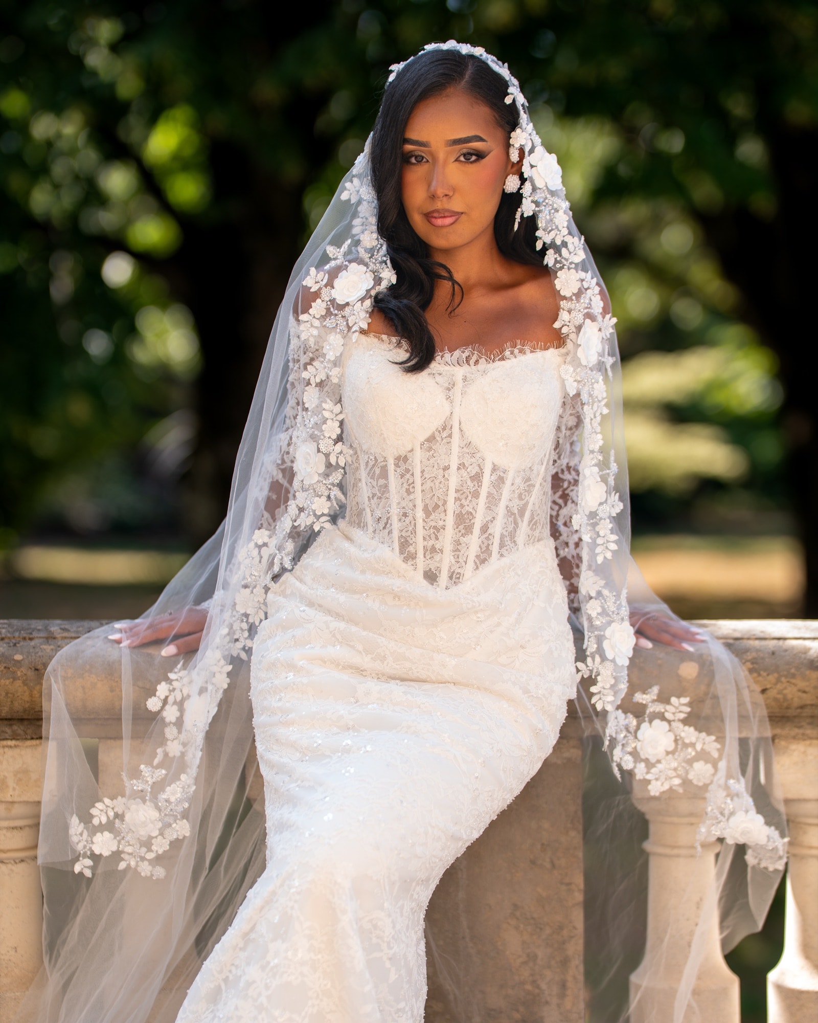 Le voile fleuri — Assise sur la balustrade, plein soleil — photographie mariage par UNPOSD