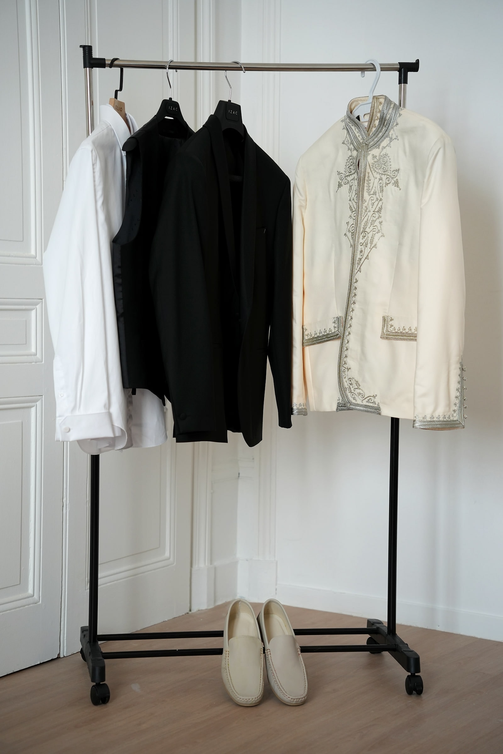 Le portant avec le costume noir, la chemise et la veste ivoire brodée