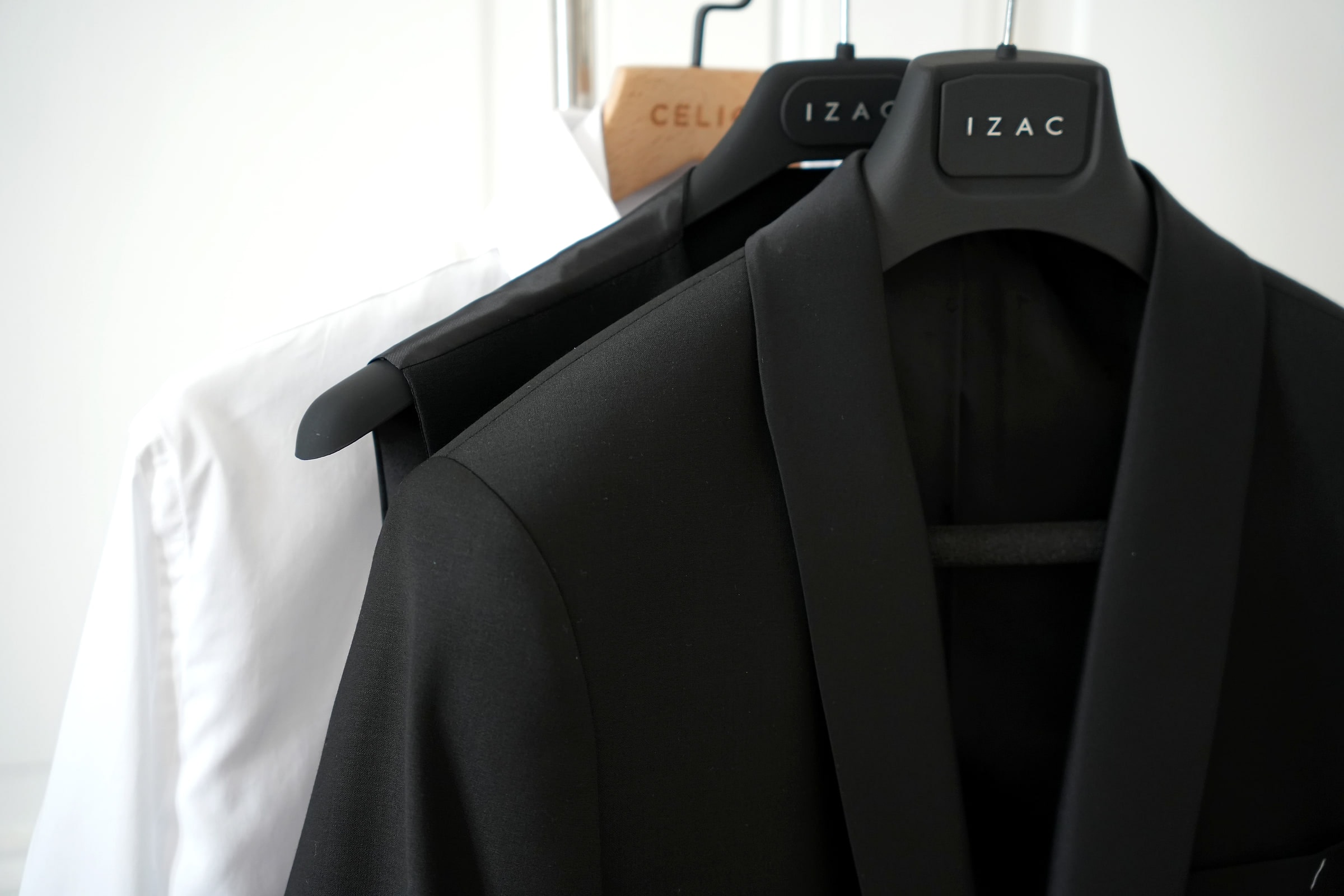 Le costume noir et la chemise blanche sur leurs cintres