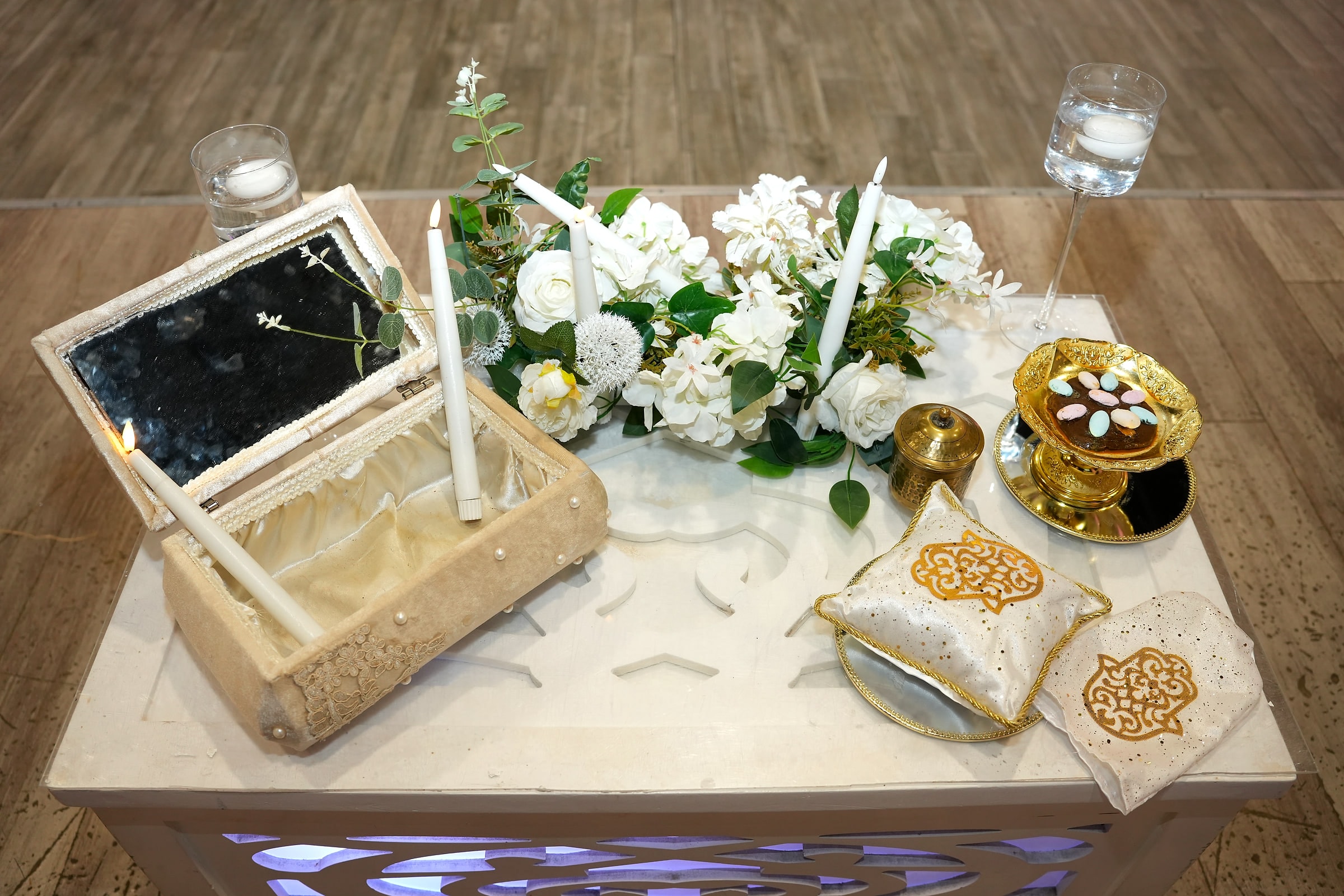 Un coffret à miroir, des bougies et des fleurs blanches sur une petite table